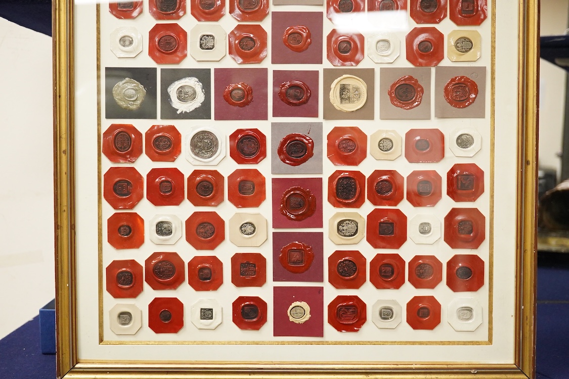 A framed display of red and white wax seals, some stamped Casolo Lausanne, 95 in total, 59cm wide